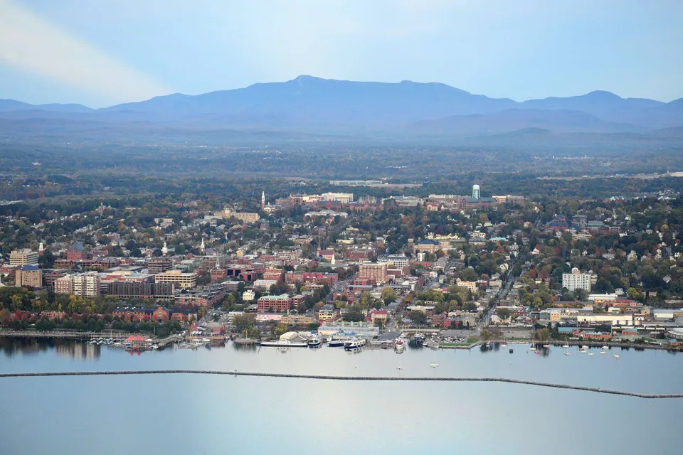 Burlington, Vermont from above, with Lake Champlain in the foreground and Mount Mansfield behind the city.