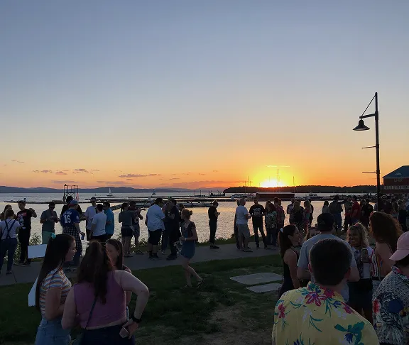 A summer crowd on a lakeside waterfront at sunset.